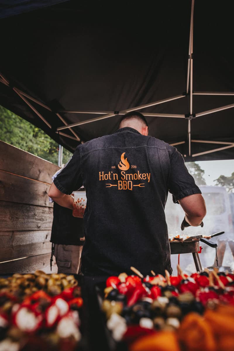 Grillmeister mit Hot’n Smokey-Logo auf dem Rücken am Buffet