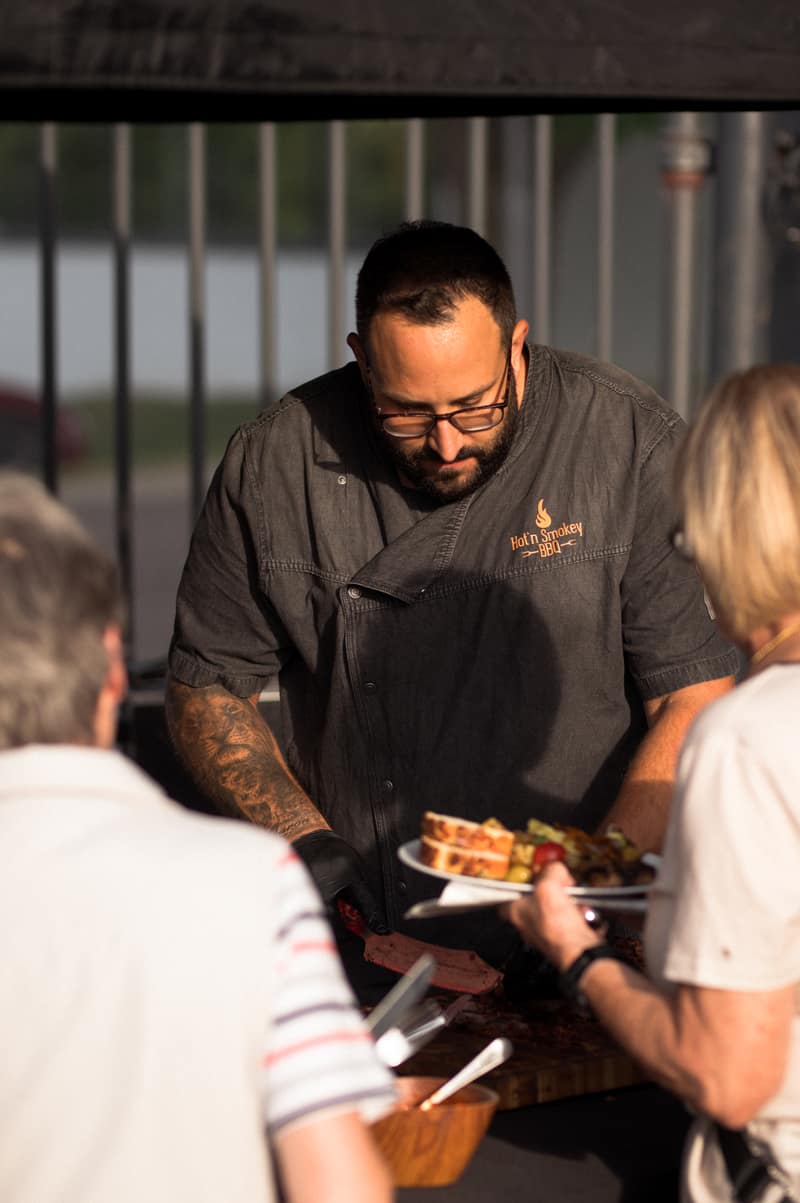 Grillmeister gibt Gästen am Buffet Essen aus