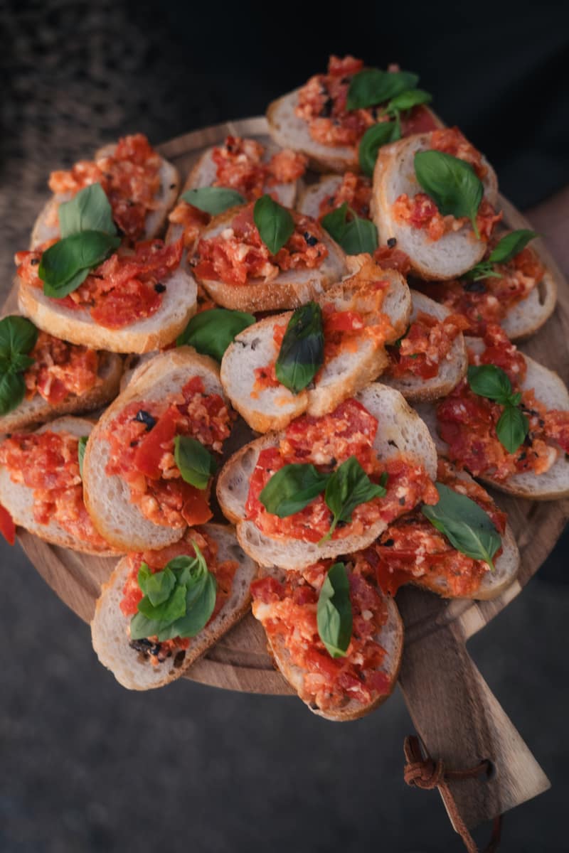 Holzbrett voller Bruschetta mit Basilikum