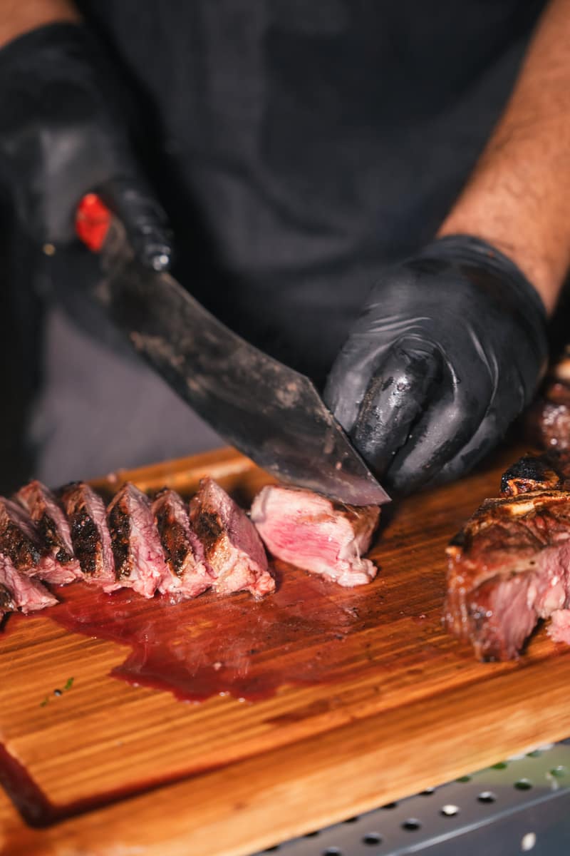 Steak wird auf dem Holzbrett aufgeschnitten