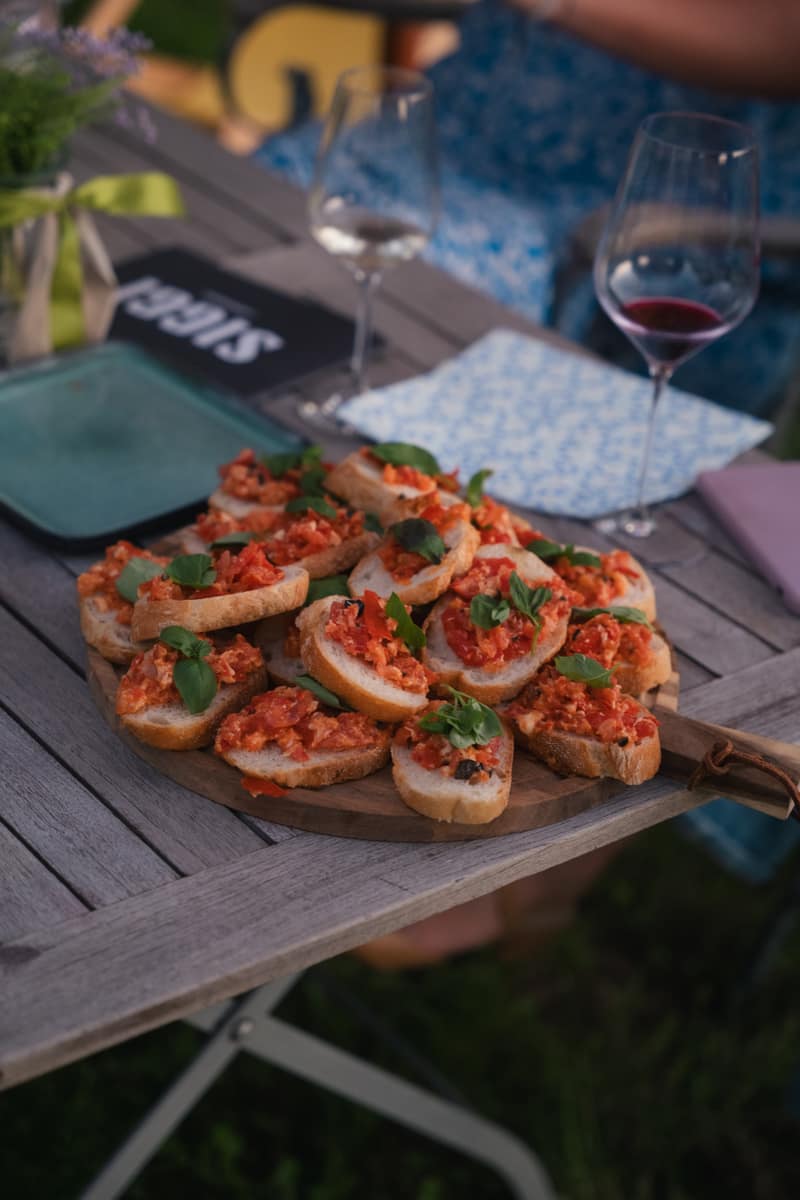 Gedeckter Gartentisch mit Bruschetta und Weingläsern