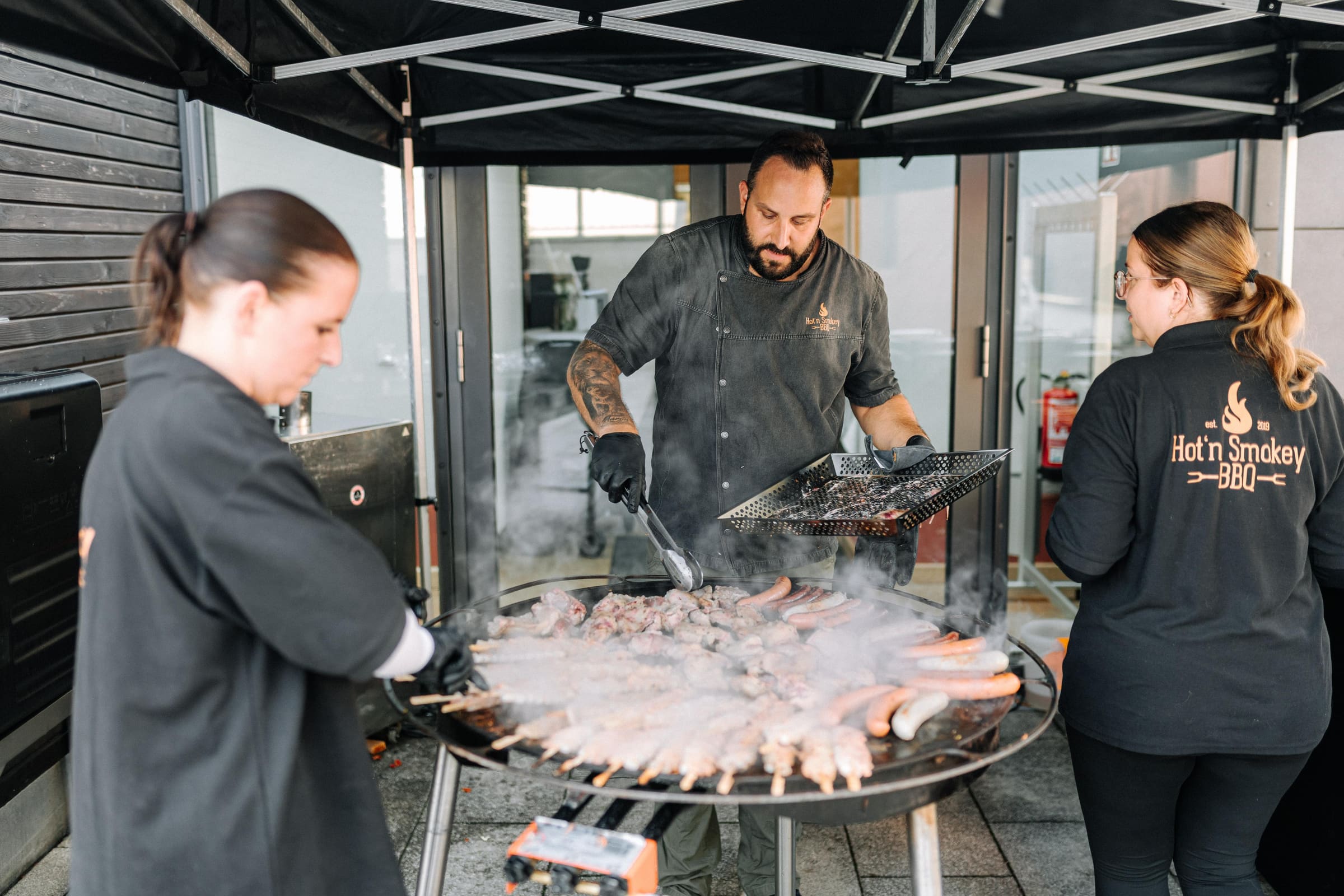 Drei Leute aus dem Team von Hot'n Smokey BBQ grillen an der Feuerplatte